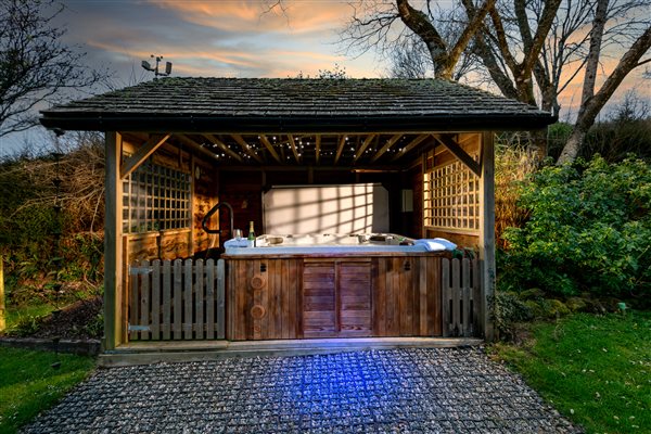 Corn Barn hot tub covered by gazebo with evening lighting